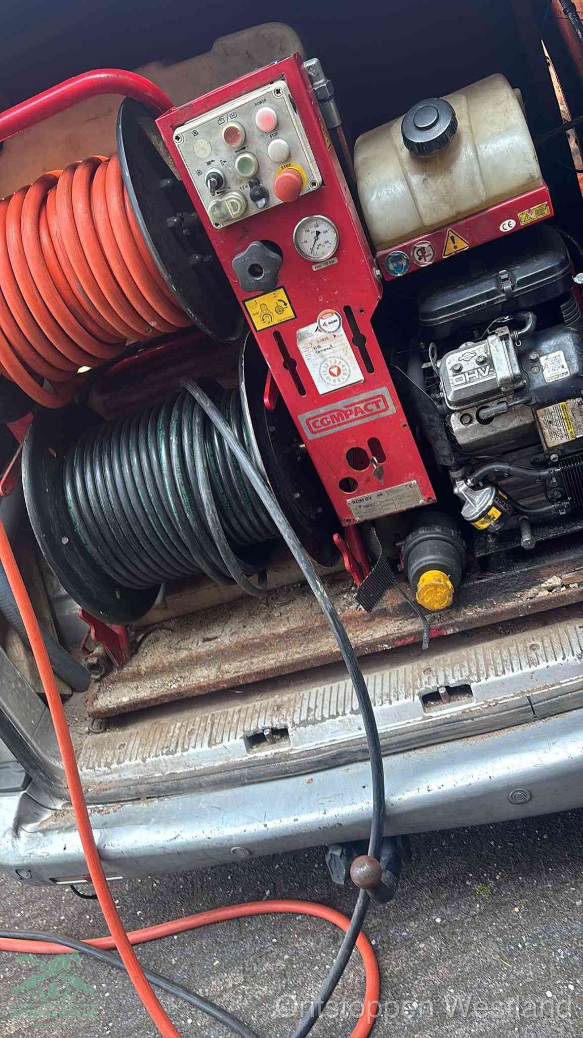 Een rood hogedruk-rioolreinigingstoestel in de laadbak van de bedrijfsbus, apparatuur voor een hardnekkige afvoerverstopping in Westland
