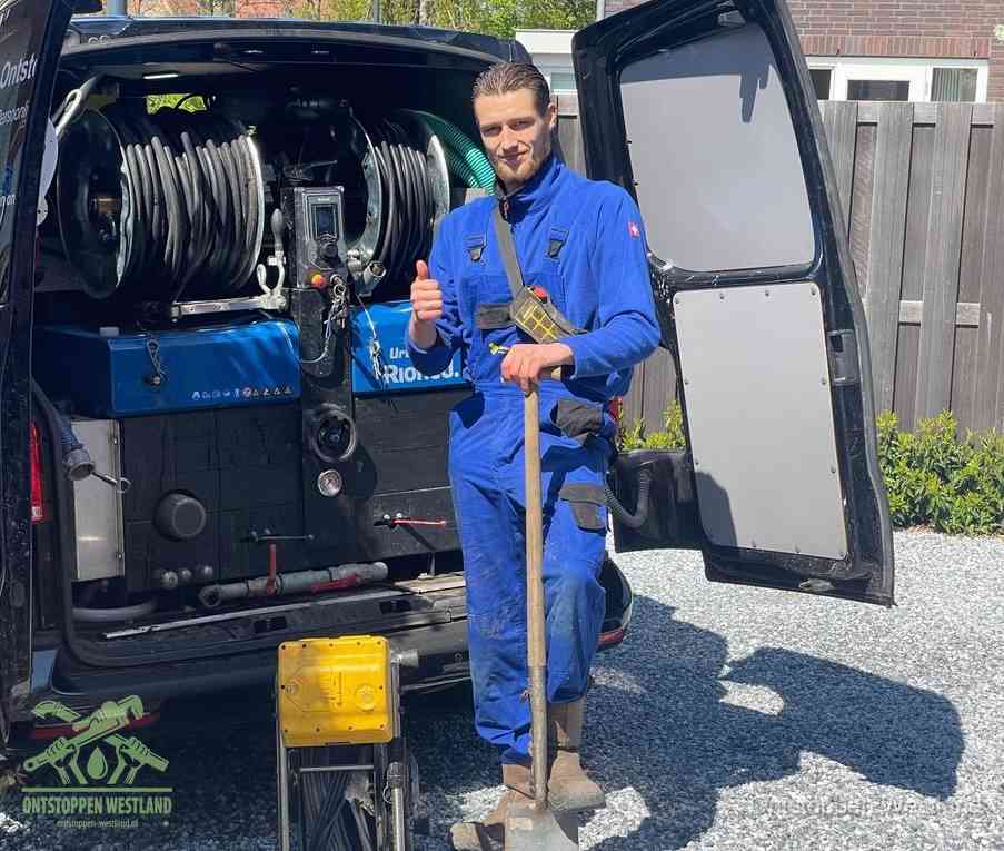 Een monteur bij de werkbus met grote hogedruk-slanghaspels, apparatuur voor hardnekkige afvoerverstoppingen in Westland