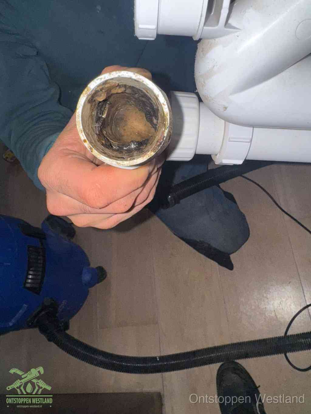 Een losgekoppelde afvoerbuis die van binnen volledig is dichtgeslibd met vet en aanslag, de meest voorkomende oorzaak van een verstopte gootsteen in Westland