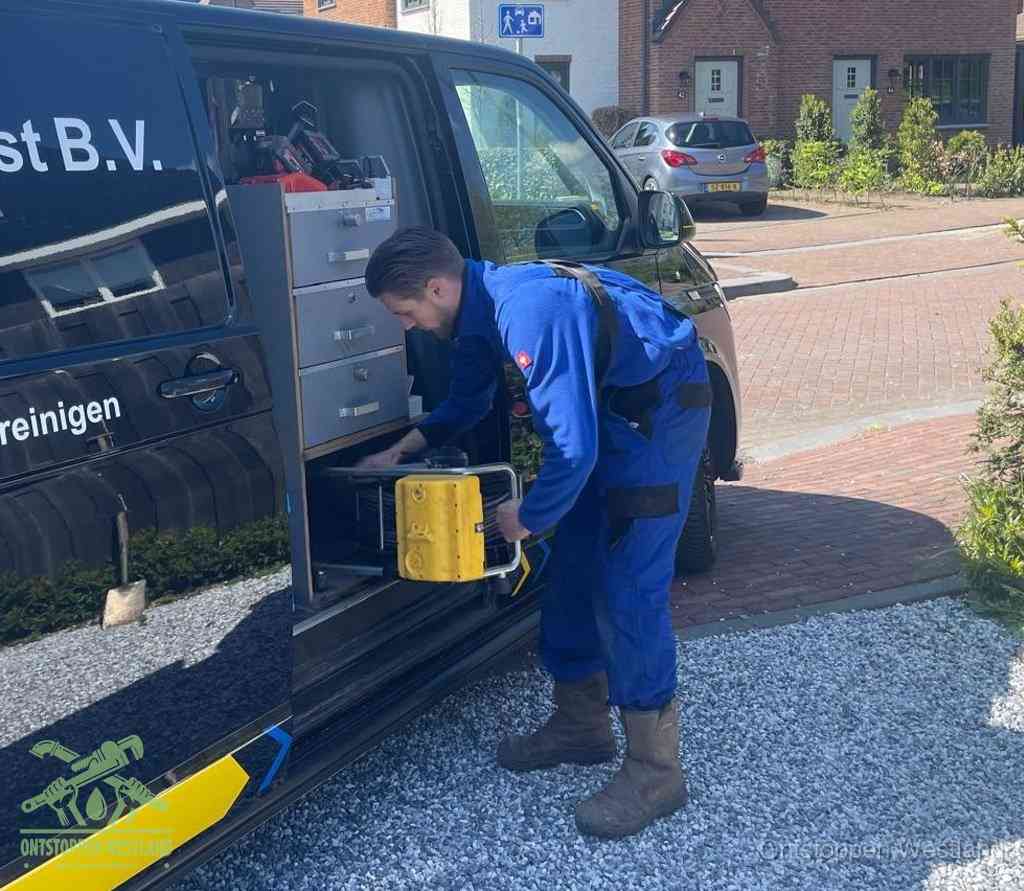 Een monteur pakt apparatuur uit de bedrijfsbus voor service aan huis, het moment om een professional in te schakelen voor een verstopte wc in Westland