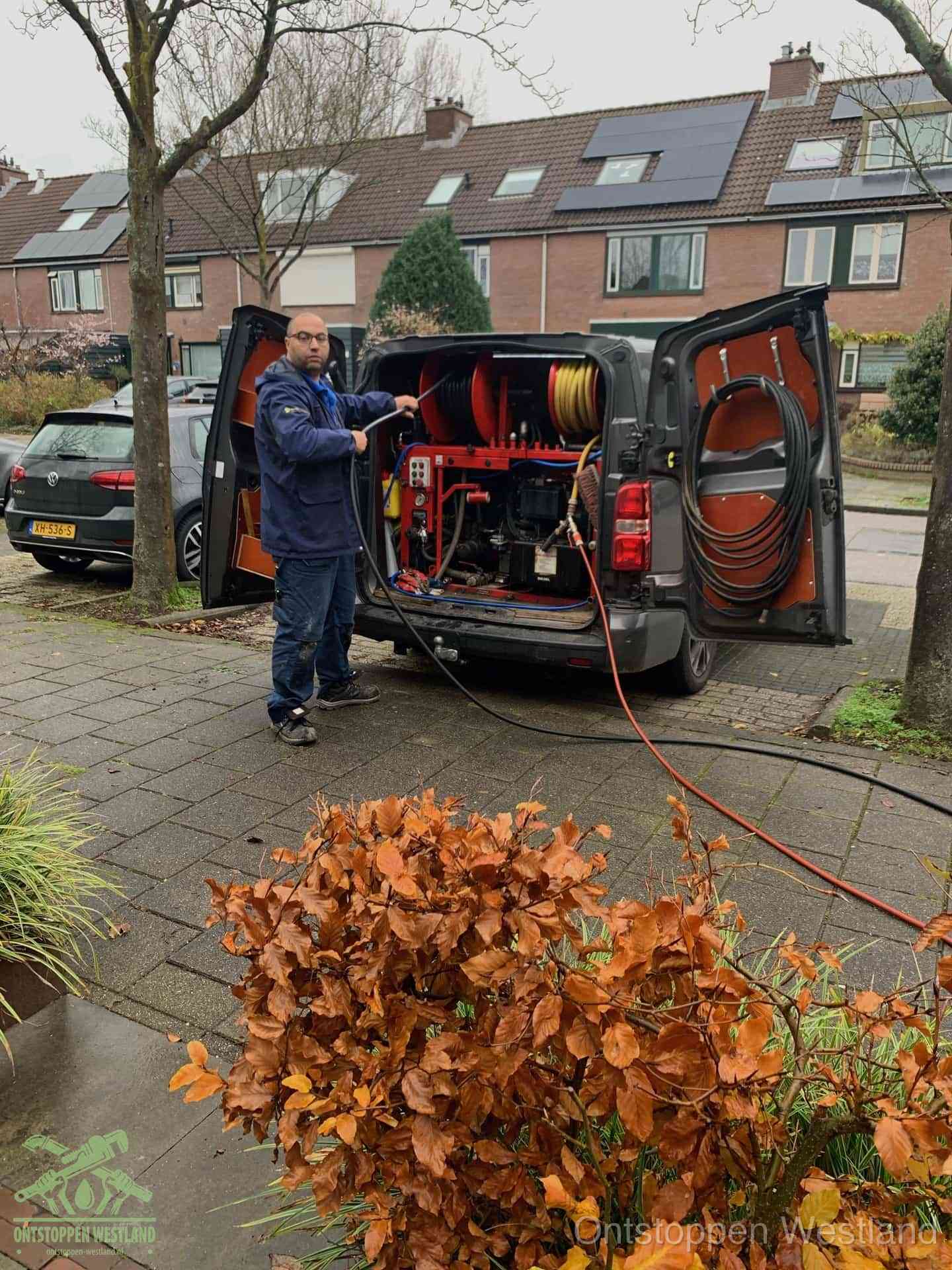 Monteur met rioolreinigingsbus levert rioolservice in de wijk in Westland
