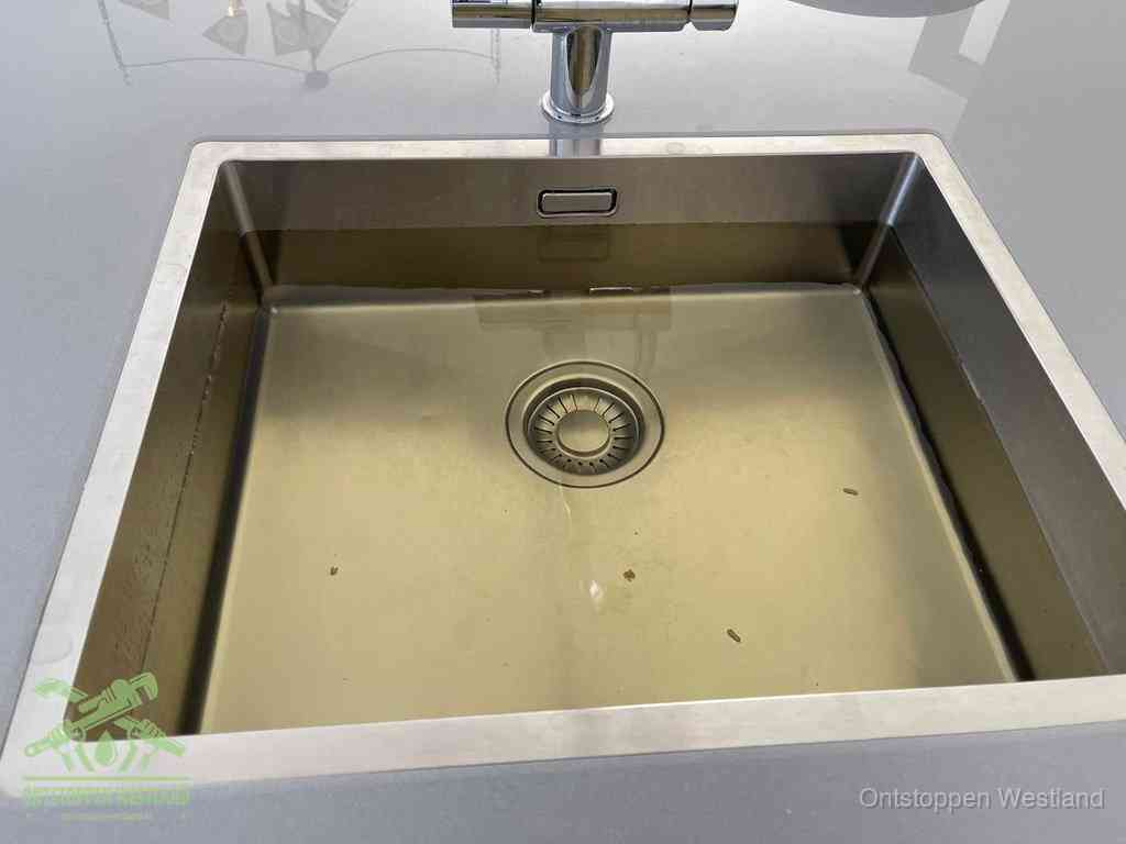 Stilstaand water in een rvs spoelbak dat niet wegloopt, een duidelijk signaal van een gootsteenverstopping in Westland